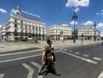 Dos personas cruzan la calle en la Puerta del Sol de la capital.