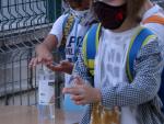 Dos alumnos de primaria se lavan las manos con gel hidroalcohólico en la puerta del colegio, el primer día de curso en Tortosa.