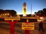 Activistas de Greenpeace con pancartas delante de la estatua con mascarilla