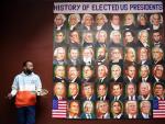 El artista indio Jagjot Singh Rubal posa junto a su obra, un mural con los rostros de los 46 presidentes de Estados Unidos, incluido el actual presidente electo, Joe Biden.