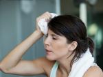 Una mujer se seca el sudor de la frente al hacer ejercicio.