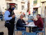 Un agente de los Mossos pidiendo este mi&eacute;rcoles a dos chicos que se pongan la mascarilla mientras no consumen en una terraza de Tarragona.