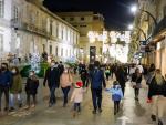 Transe&uacute;ntes pasean bajo las luces navide&ntilde;as, llevando mascarilla, alguno con gorro navide&ntilde;o, en Vigo, Galicia (Espa&ntilde;a), a 25 de diciembre de 2020