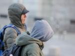 Dos jovenes se protegen del fr&iacute;o con abrigos y gorros mientras pasean durante un d&iacute;a de fr&iacute;o y viento por Madrid