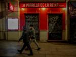 Dos j&oacute;venes pasan por delante de un restaurante cerrado durante el primer d&iacute;a del toque de queda a las 10 de la noche, en Madrid (Espa&ntilde;a), a 25 de enero de 2021.