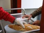 Un voluntario (i) trae comida a una persona (d) como parte del reparto diario de alimentos del Comedor Social San Jos&eacute;, en Puente de Vallecas, Madrid (Espa&ntilde;a), a 5 de febrero de 2021.