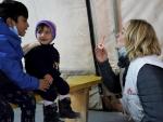 Una supervisora juega con dos ni&ntilde;os en la sala de espera de la cl&iacute;nica de M&eacute;dicos Sin Fronteras en un campo de refugiados en Lesbos.