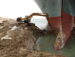 Una excavadora horada el terreno para liberar al buque Ever Given, encallado en el Canal de Suez.