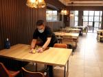 Un hombre prepara una mesa en un restaurante de Lleida.