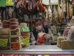 Archivo - Un carnicero trabaja con mascarilla en un mercado.
