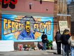 Un grafiti con la imagen de George Floyd y flores en su memoria, en el lugar donde el afroamericano muri&oacute; a manos de un polic&iacute;a mientras era arrestado, en Mine&aacute;polis (Minnesota, EE UU).