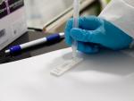 Una trabajadora sanitaria sostiene un test de ant&iacute;genos