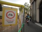 Una bicicleta circula por la acera en Passeig de Sant Joan pese al cartel del Ayuntamiento de Barcelona que lo proh&iacute;be.