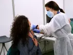 Archivo - Un empleada sanitaria suministra la vacuna contra la Covid-19 en el dispositivo de vacunaci&oacute;n puesto en marcha en unpolideportivo