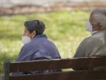 Un hombre y una mujer mayores, sentados en un banco y con mascarilla, en el Parque del Manzanares, el d&iacute;a en que entra en vigor el uso obligatorio de mascarilla incluso con distancia de seguridad, en Madrid (Espa&ntilde;a), a