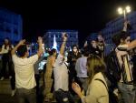 Varios j&oacute;venes saltan y bailan en la Puerta del Sol de Madrid durante la noche en la que ha finalizado el estado de alarma y el toque de queda.