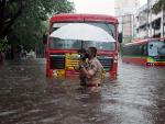 Un polic&iacute;a ayuda a un conductor a cruzar una calle inundada por el cicl&oacute;n Tauktae en Bombay.