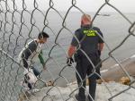 Un guardia civil ayuda a uno de los inmigrantes en uno de los espigones fronterizos de Ceuta.
