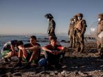 Miembros del ej&eacute;rcito observan a un grupo de inmigrantes menores a su llegada a la playa de El Tarajal en Ceuta este mi&eacute;rcoles.