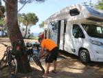 Un hombre arregla su bicicleta junto a su autocaravana en un camping de Palamós (Girona).