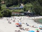 Varias personas se ba&ntilde;an y toman el sol en una playa del municipio de Mar&iacute;n, en Pontevedra, este s&aacute;bado.