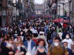 Cientos de personas, muchas con mascarillas por la pandemia de covid-19, caminan por la calle Madero, en el Centro Histórico de Ciudad de México.