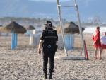 Un agente de la Polic&iacute;a Local y dos socorristas junto al puesto de vigilancia en la playa de la Malvarrosa (Valencia).