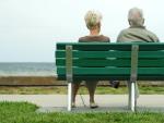 Una pareja de ancianos, sentados en un banco.