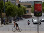 Un joven en bicicleta pasa junto a un term&oacute;metro que marca 45 grados cent&iacute;grados en Sevilla.
