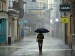 Un hombre camina, este lunes, bajo una intensa lluvia por el centro de la ciudad de Gand&iacute;a, en Valencia.