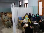 Estudiantes separados entre hombres y mujeres por un biombo, en un aula de la Universidad Mirwais Neeka, en Kandahar, Afganistán.