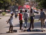 Personas observan un cadáver de un hombre famélico que yace a unos pocos metros del Palacio Nacional, hoy en Puerto Príncipe.