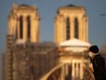 Una persona con mascarilla camina junto a la catedral de Notre Dame en París (Francia).