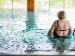 Mujer entra en la piscina del balneario para tratar su osteoporosis