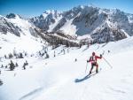 Un hombre hace esqu&iacute; de traves&iacute;a en las monta&ntilde;as sobre la nieve, explorando los Dolomitas.