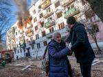 Una mujer mayor, ayudada a huir de un edificio en llamas en Kiev.