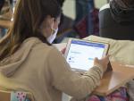 Una alumna en clase ante una tableta digital