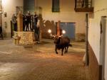Un toro embolado pasa por delante de unos espectadores en Aldover, en el Baix Ebre