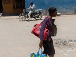 Una mujer carga con sus enseres personales tras verse forzada a abandonar su casa en el barrio de Tabarre, en Puerto Pr&iacute;ncipe (Hait&iacute;), a causa de la guerra entre bandas criminales desatada en la zona.
