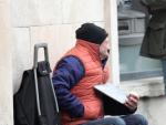 Archivo - Arxiu - Home roba d'abric i assegut en una caixa, demana diners en el carrer, en imatge d'arxiu