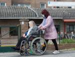 Una mujer traslada a una mujer de avanzada edad en silla de ruedas frente a la Residencia de Mayores As G&aacute;ndaras (Lugo).