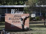Un agente de Polic&iacute;a deposita flores en la entrada de la escuela de primaria Robb, en Uvalde (Texas, EE UU), donde un joven mat&oacute; a 19 ni&ntilde;os y dos profesoras.