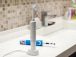 Rechargeable, electric toothbrush, close-up. Against the backdrop of a bathroom in white. Water faucet and white sink