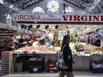 Una mujer camina frente a un puesto de verduras en el Mercado Central de Valencia.