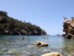 Turistas en la playa rocosa de Cala Deia en Mallorca