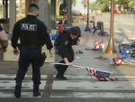 Un polic&iacute;a recoge una bandera abandonada tras el tiroteo en Highland Park, Illinois (EE UU), donde un joven dispar&oacute; contra la multitud durante el desfile del D&iacute;a de la Independencia.