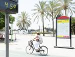 Una mujer en bicicleta por Sevilla junto a un term&oacute;metro que marca 45 grados.