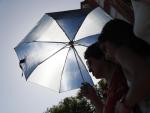 Una mujer y su hija se cubren del sol con un paraguas en Madrid.