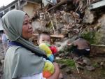 Una madre sostiene a su hijo frente a su casa da&ntilde;ada despu&eacute;s de un terremoto de magnitud 5,6, en Cianjur, Indonesia, el 22 de noviembre de 2022.