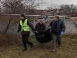 Forenses y polic&iacute;as transportan en una bolsa restos humanos hallados en una fosa com&uacute;n en la localidad de Pravdyne, en las afueras de Jers&oacute;n, Ucrania.